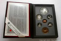 Front view of set showing seven coins housed in foam within black display case with certificate on left side.