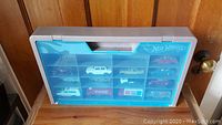 Plastic Hot Wheels branded display case with translucent blue lid and 13 die cast vehicles inside compartments