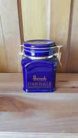 Front view of cobalt blue ceramic storage canister with gold Harrods Food Halls logo and metal clasp lid