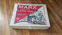 Top-down view of the original Marx train set box with red and black printing depicting a steam locomotive.