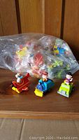 Three vintage plastic push-toy vehicles featuring Peanuts characters including Snoopy in a red airplane, a blue train with a male character, and a green car with a female character.