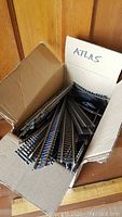 Open cardboard box marked 'ATLAS' filled with multiple curved model railway track pieces.