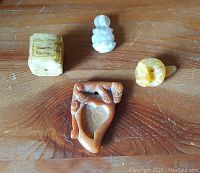 Top-down view of all four netsuke laid on wooden surface showing patina and detail