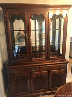 Cherry finish wooden hutch with glass display cabinet on top, showing all doors and drawers, with one missing handle visible.