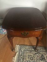 Front view of cherry end table showing top, single drawer with brass bail pull and cabriole legs