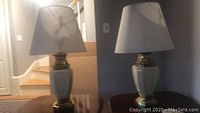 Two matching table lamps on separate wooden side tables, with shades on, showing front view and overall presentation