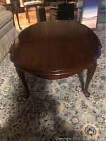 Front view of rectangular cherry wood coffee table with rounded edges, carved legs, and polished surface.