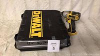 Closed DEWALT-branded black carrying case with yellow logo and lot identification card