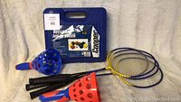 Complete Cooper bocce set in blue carrying case with multiple bocce balls and a pallino ball visible, accompanied by four badminton rackets with yellow and blue frames and black handles.