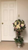 Full view of wedding topiary showing spherical foam flower ball and base arrangement against white door.