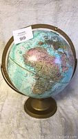 Front view of the older world globe showing Africa and Europe on the globe surface, mounted on a bronze-colored metal stand.