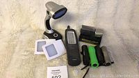Overview of assorted lights including gooseneck lamp, LED panels, black multi-LED flashlight, three mini flashlights and unopened bicycle light in packaging.