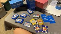 Overview of multiple stacks of Pokemon trading cards laid out on a table with two storage boxes, three dice, and some loose cards including special edition and World Championship cards.