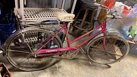 Side profile of the full vintage Columbia Tourist bicycle showing pink frame, chain guard, fenders, seat, tires.