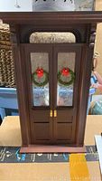 Front view of the handmade wooden double door with Christmas wreaths on glass panels and number 11 above doors.