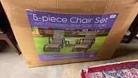 Box showing the 5-piece chair set with footrests and side table, unopened.
