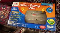 Front of the unopened APC battery backup box showing the product image and key features.