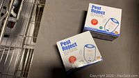 Two unopened boxes of Pest Reject ultrasonic pest repellent units displayed on a surface.