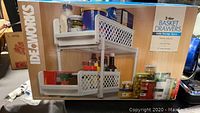 Box image showing 2-tier white basket drawers with various kitchen items in baskets