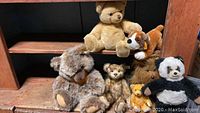Overview of all seven Steiff plush animals on wooden shelf