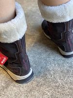 Close-up photo showing the back of the boots with faux fur lining and New Balance branding on the sole and heel.