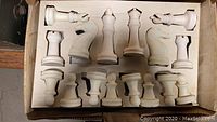 Chess pieces arranged inside box fitted with foam, showing set of large white plastic/composite pieces.