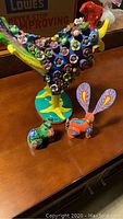 Full view of the large painted chicken figurine surrounded by two small bunny figurines on a wooden surface.