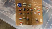 Collection of vintage political campaign buttons displayed on cardboard including Ford, McGovern, Willkie, Dewey, and watermarked with election-related slogans