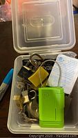 Clear plastic container with assorted padlocks and combination locks including green GE lock and yellow padlock.