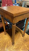 View of side table showing burl wood top, scalloped apron, and turned legs