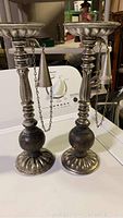 Full view of both vintage candlesticks standing side by side showing wood and metal construction with attached snuffers.