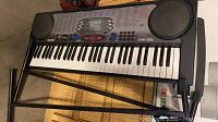 Full view of Casio CTK-551 keyboard on black metal stand showing keyboard keys and speaker units.