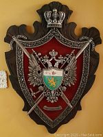 Full view of the vintage coat of arms plaque mounted on a wood shield with two crossed swords and a crowned double-headed eagle.