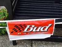 Close-up of Bud Racing logo on red background with checkered flag design on PVC banner