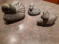 Three original painted stone duck sculptures shown together on countertop.