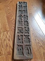 Full view of the long rectangular wooden cookie template with multiple carved shapes for cookies.