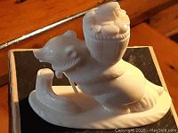 Front side angled view of the white polar bear carving on a black box under warm lighting showing the basket on its back and the bear's head profile.