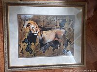 Front view of framed lion artwork showing the lion against a textured primitive style background with decorative wood frame and double matting.