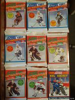 Nine unopened packs of Score NHL hockey cards from 1990 and 1991 displayed in three rows of three. Packs feature colorful artwork with hockey players in action and Score branding.