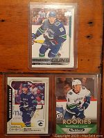 Front of three Vancouver Canucks rookie cards showing Elias Pettersson, Adam Gaudette, and Brock Boeser in plastic sleeves.