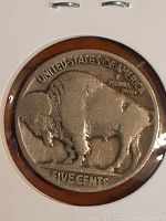 Close-up of the buffalo side of a heavily worn U.S. Buffalo Head Nickel coin, showing details of the buffalo and inscriptions around it.