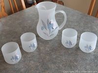 Full set including frosted glass pitcher and four matching frosted glasses with floral decoration.