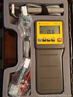 View of Texas Instruments CBL handheld device in foam case with sensor probes and cables packed alongside