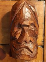 Front view of the wooden carved face highlighting facial features and carving marks.