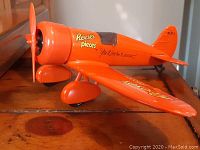 Side view of the orange metal airplane coin bank with Reese's Pieces branding and propeller on front.