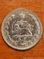 Close-up photo of one silver 5 Rials coin with Lion and Sun emblem, crown and sword, resting on wood surface