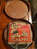 Metal film case open showing vintage Scrappy 16mm movie film original box and metal film reel inside.