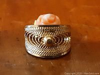 Front view of the gold-tone pendant showcasing intricate rope design and central carved rose.