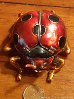 Top view of the red enameled metal ladybug ring holder showing black spots and gold legs.