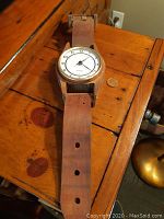 Photo showing the wooden wrist watch dial, strap, and clasp on a wood surface with a coin nearby for scale.